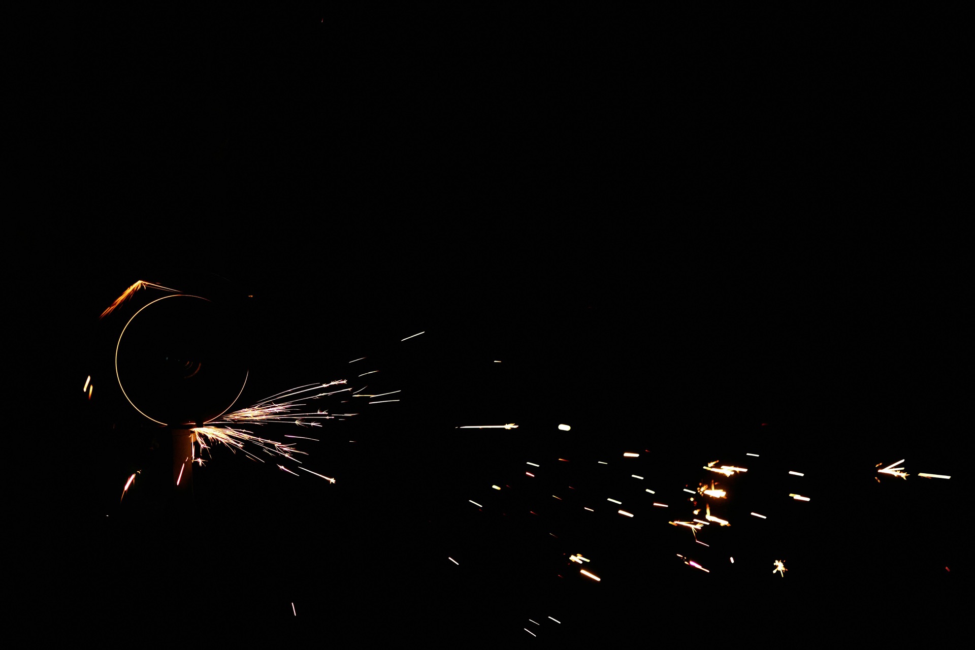 Angle grinder throwing sparks against a dark field — close-up of material contact